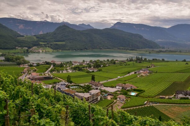 Kurzurlaub Trentino-Südtirol, Italien, Der Kalterer See, eingebettet in die Südtiroler Weinberge, glitzert t