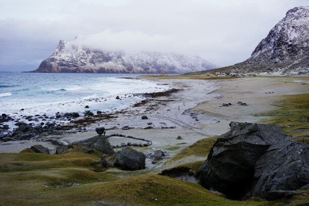 10 Tage Lofoten & Vesterålen, Norwegen, Am Strand von Uttakleiv treffen weiß verschneite Berge auf grüne Wie
